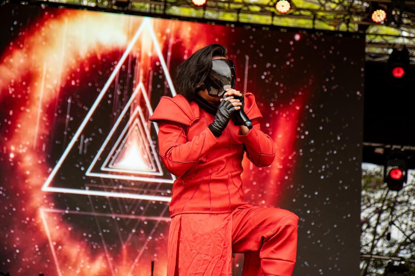 El vocalista de rodillas frente a un triángulo de luz