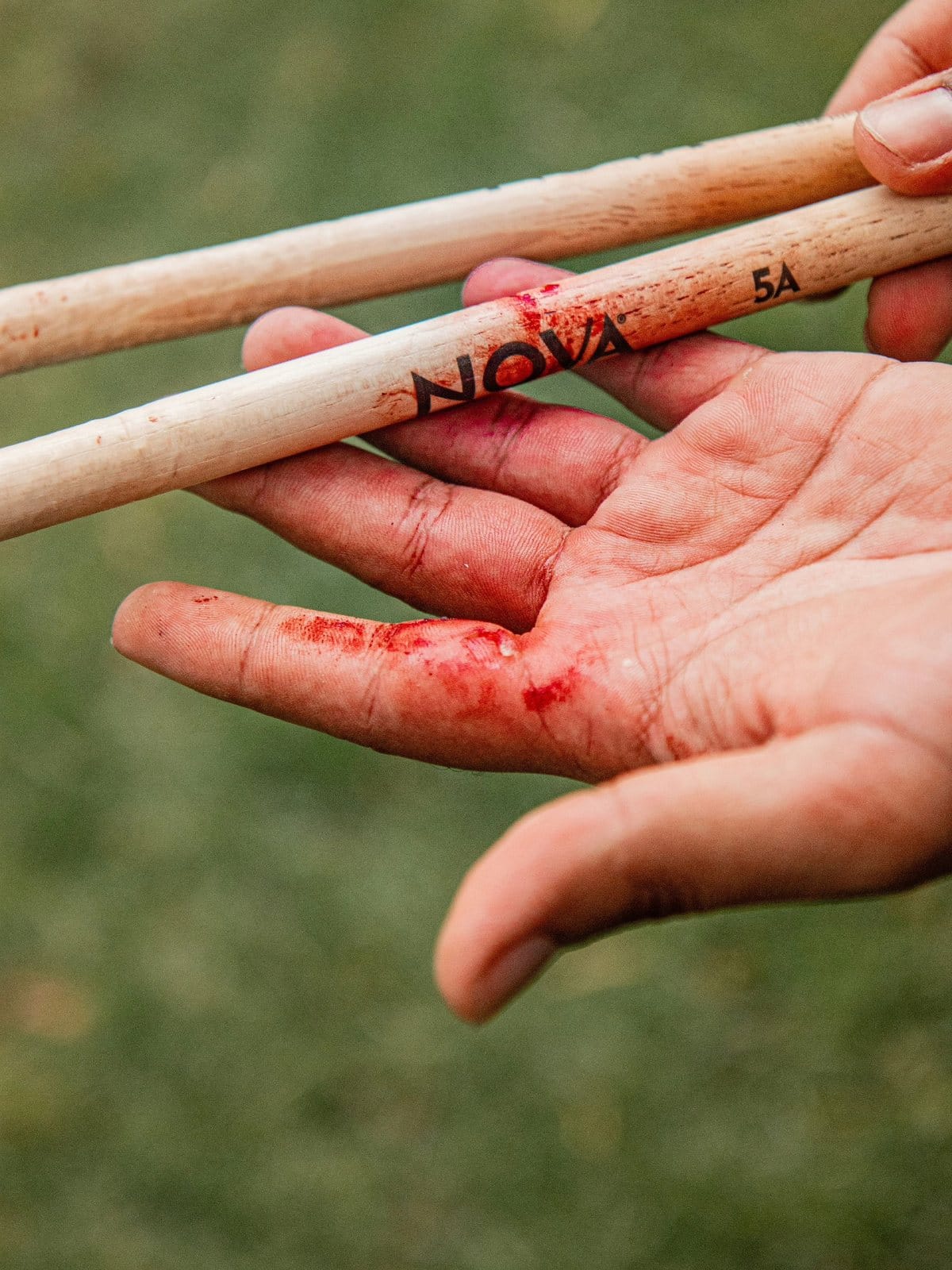 Las baquetas y la mano con sangre del baterista después del show