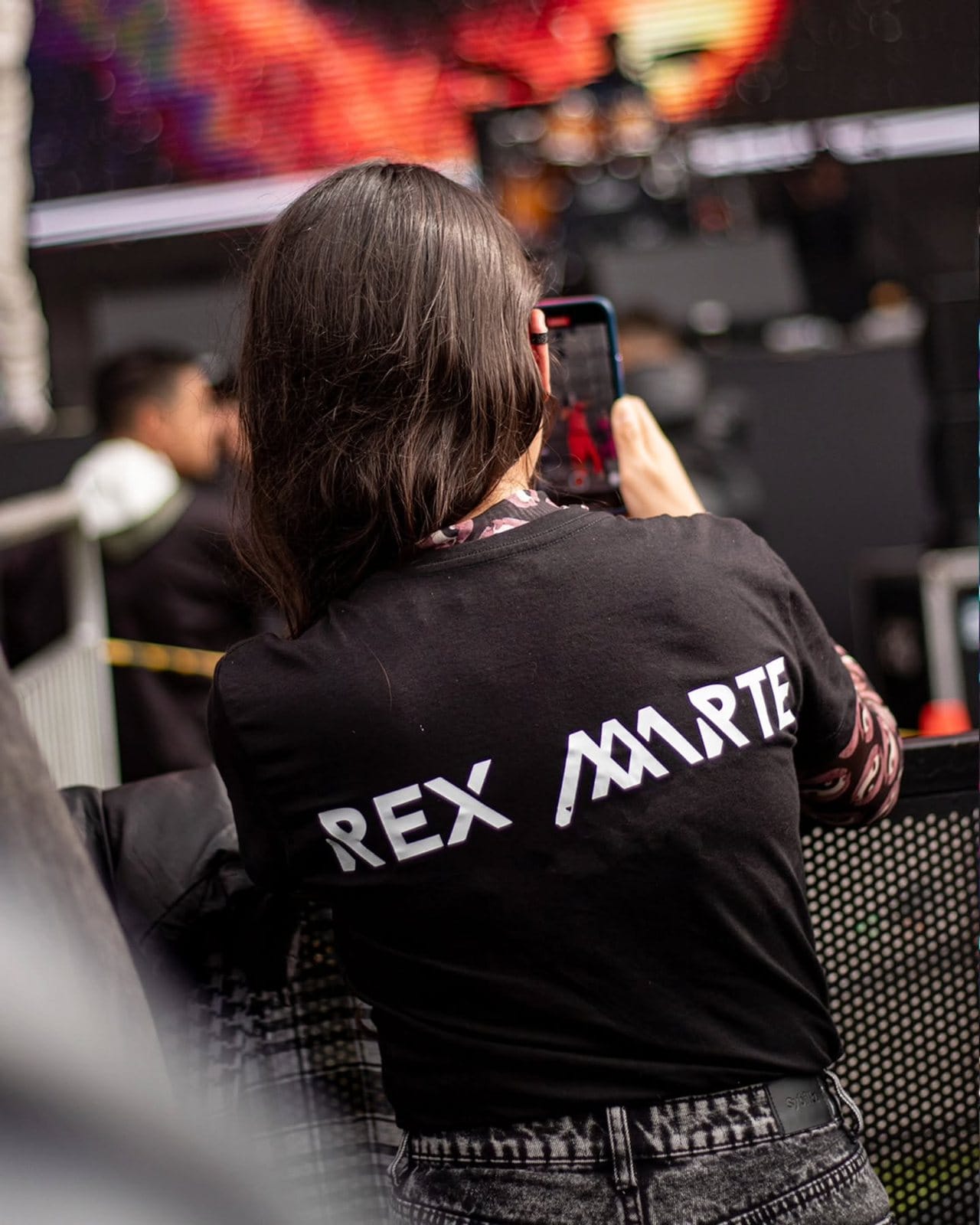 Una fan con la camiseta de Rex Marte grabando el show con su celular