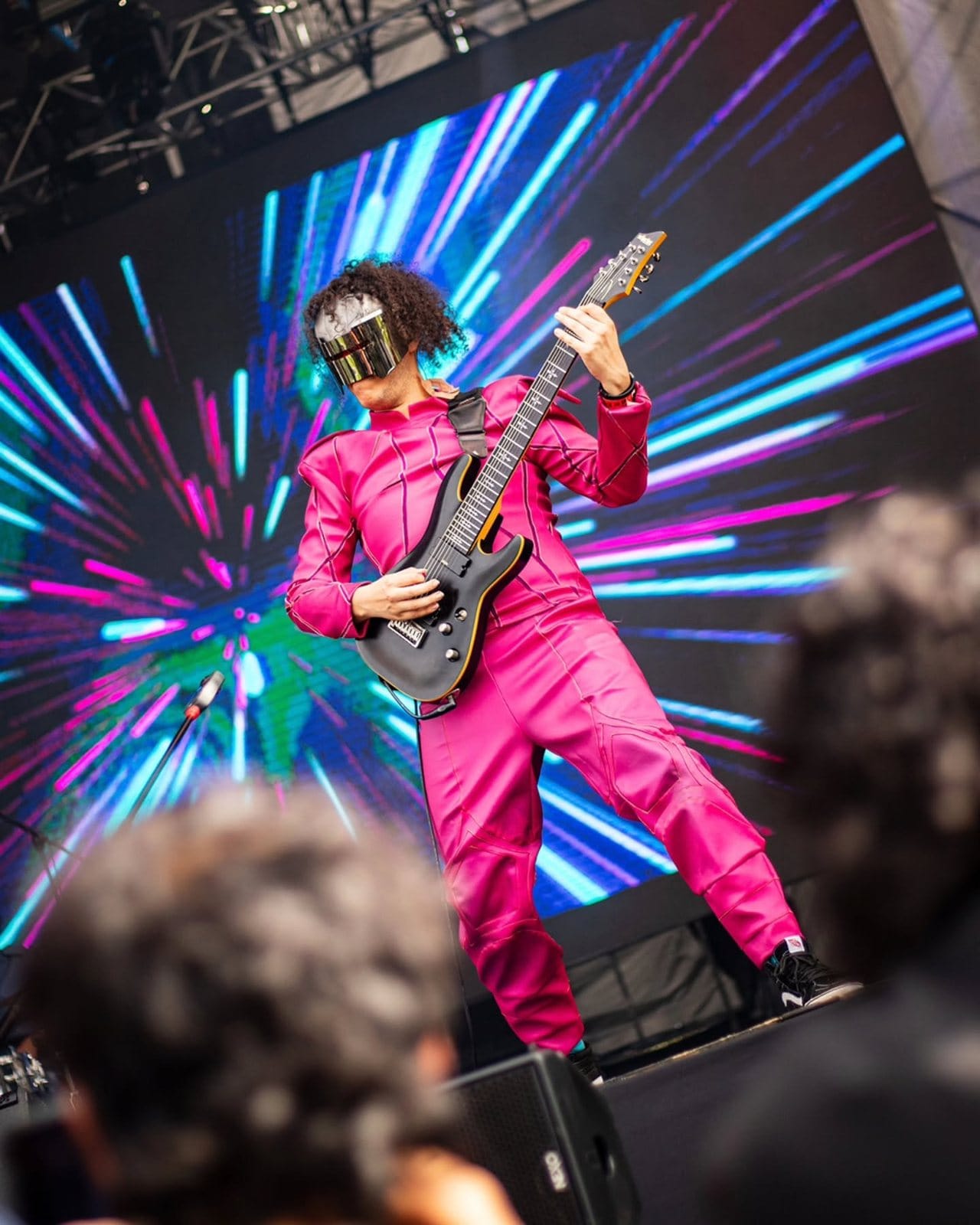 El guitarrista de Rex Marte, de rosado, frente a luces de colores
